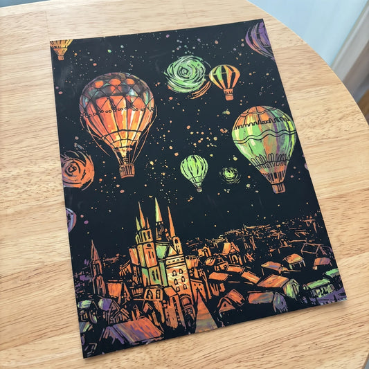 Glowing ScratchBoard showing balloons over a city, revealing green glow-in-the-dark pigment